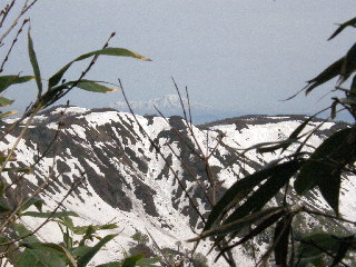 右前方の稜線の先に雪を被った山が